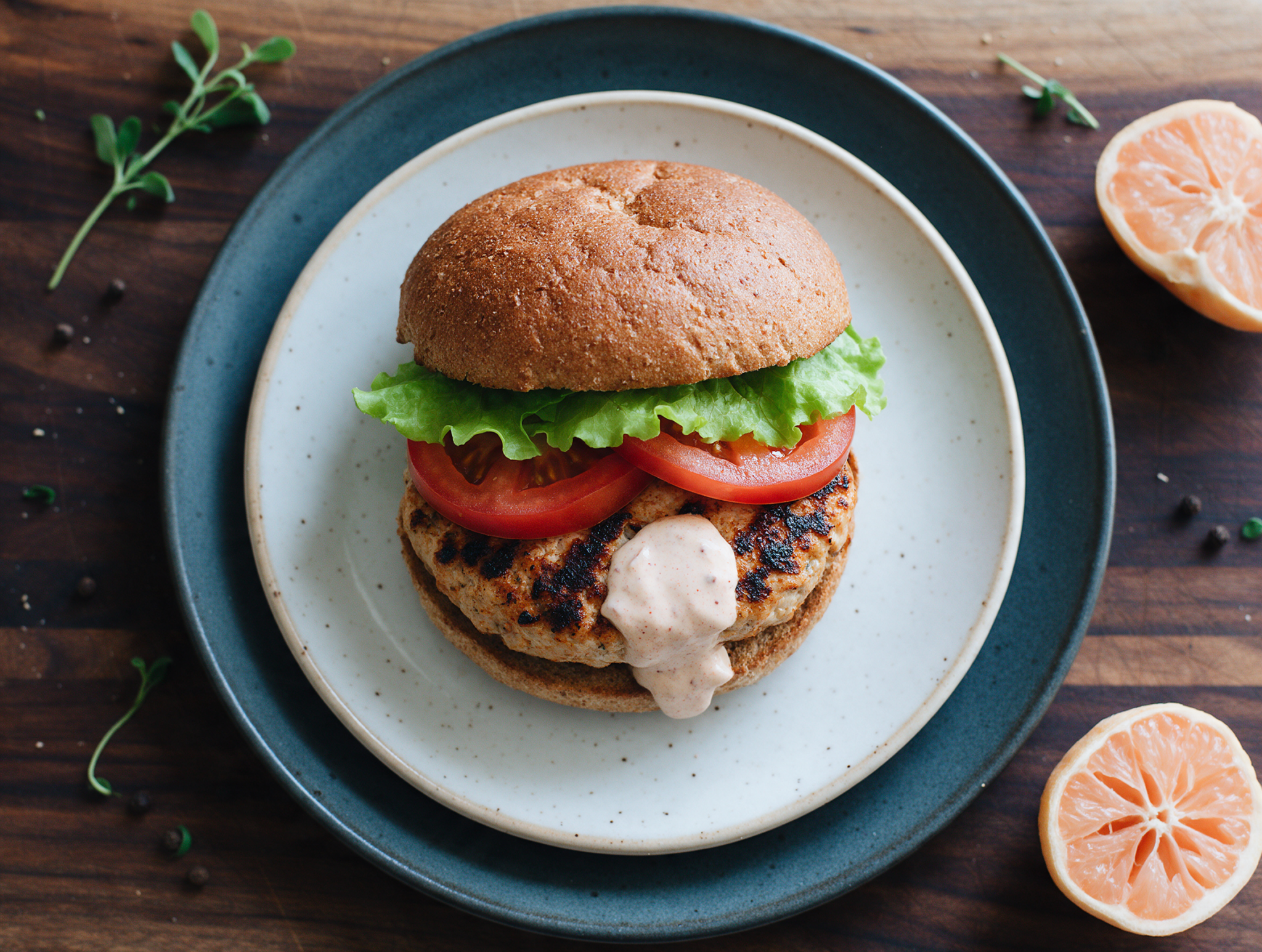 Smoked paprika turkey burger on a toasted bun with lettuce and tomato, yogurt sauce visible on a dark wood board